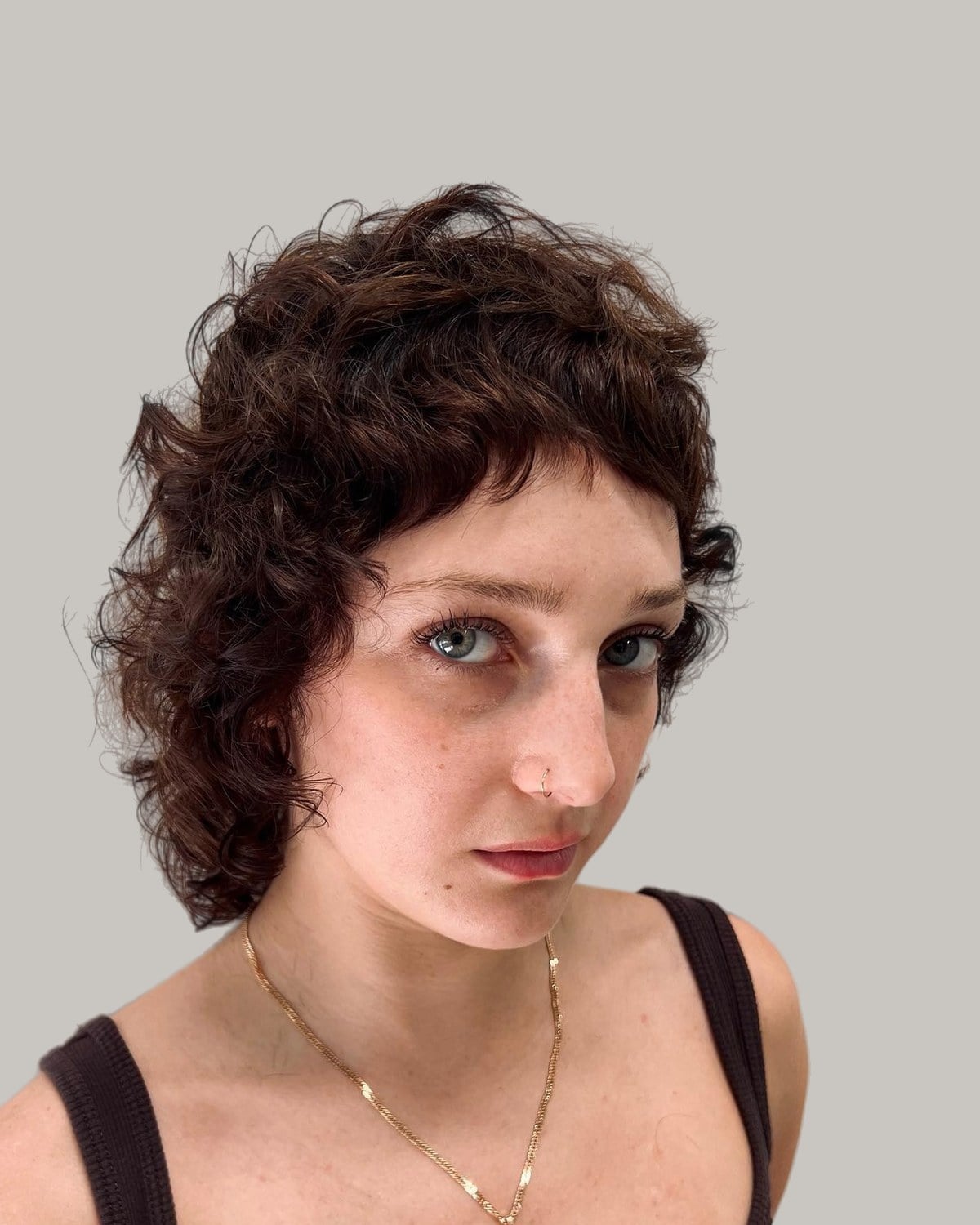 Woman with a curly brown shag and short curly bangs