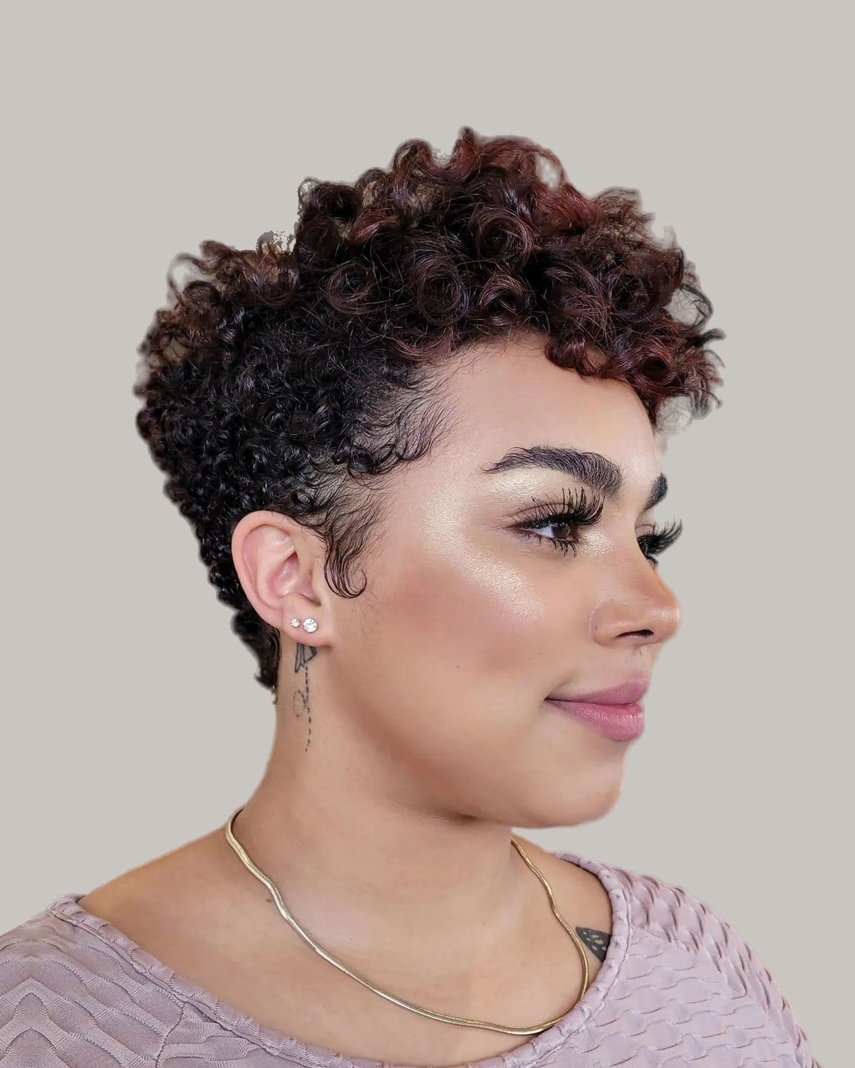 Woman with short tapered burgundy-black coils, looking to the side