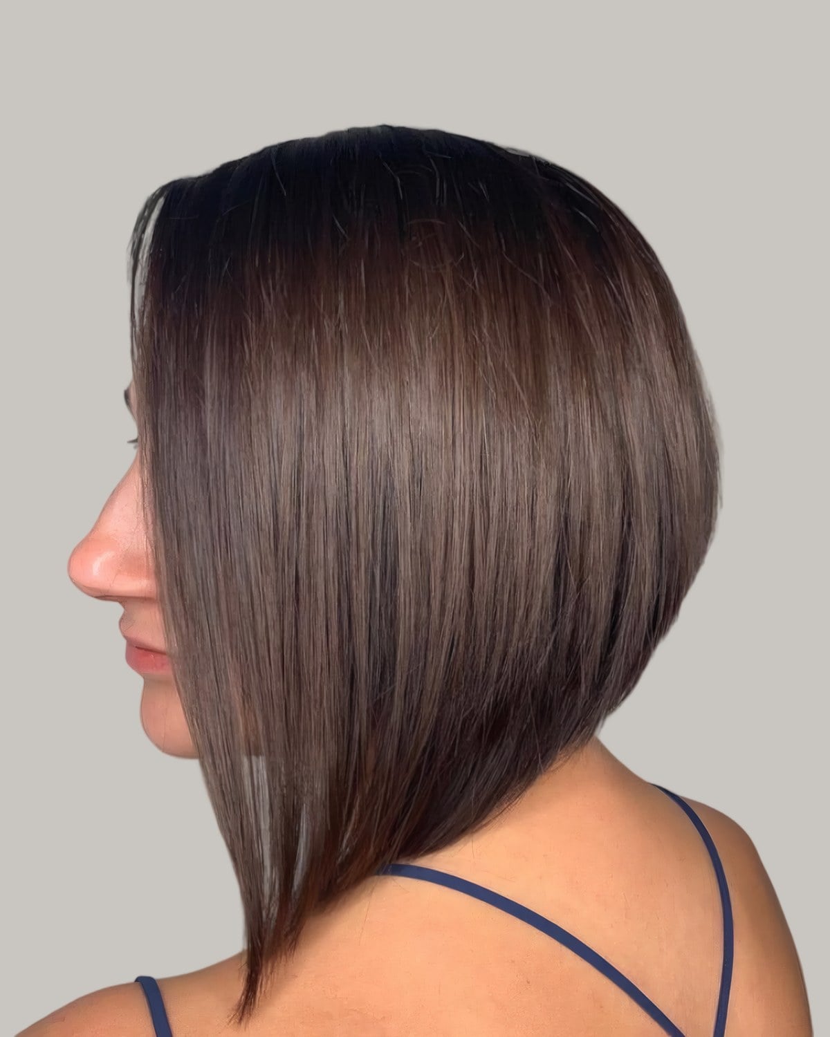 Woman with a glossy brown A-line bob, seen from behind at an angle