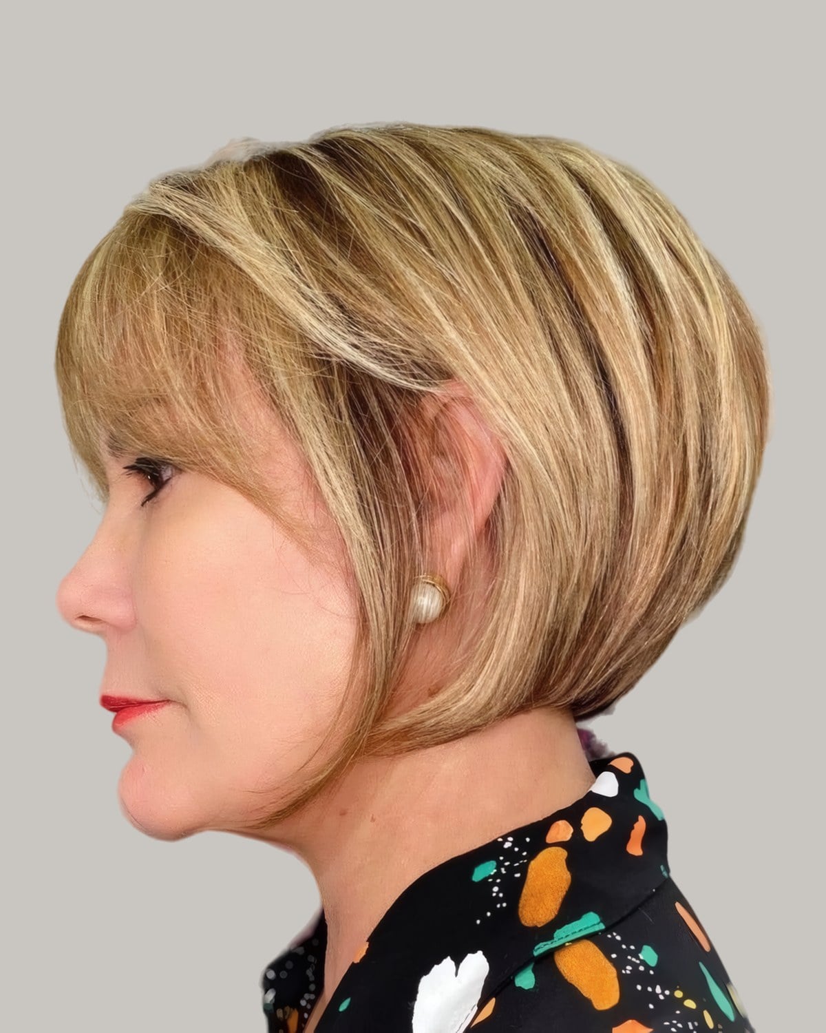 Woman with a honey-blonde rounded bob and side bangs, in profile