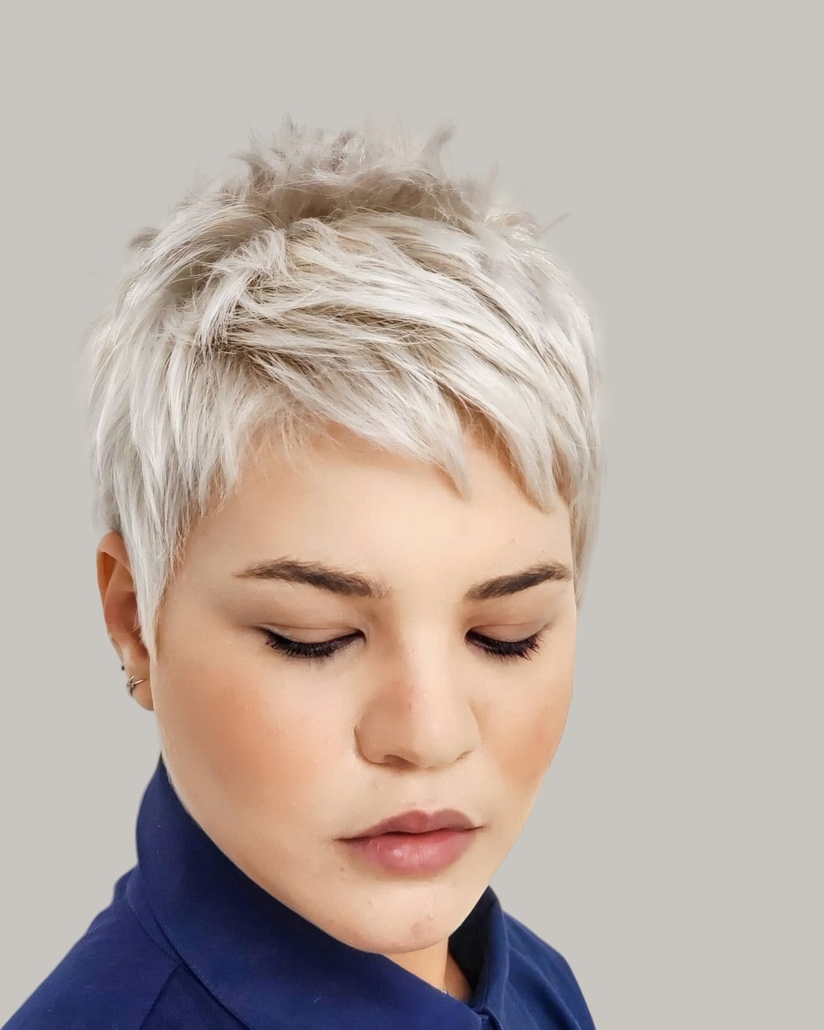 Woman with a spiky platinum pixie and short bangs, eyes closed