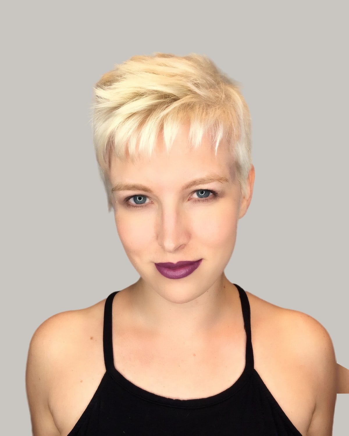 Woman with a choppy platinum pixie and short bangs, facing the camera