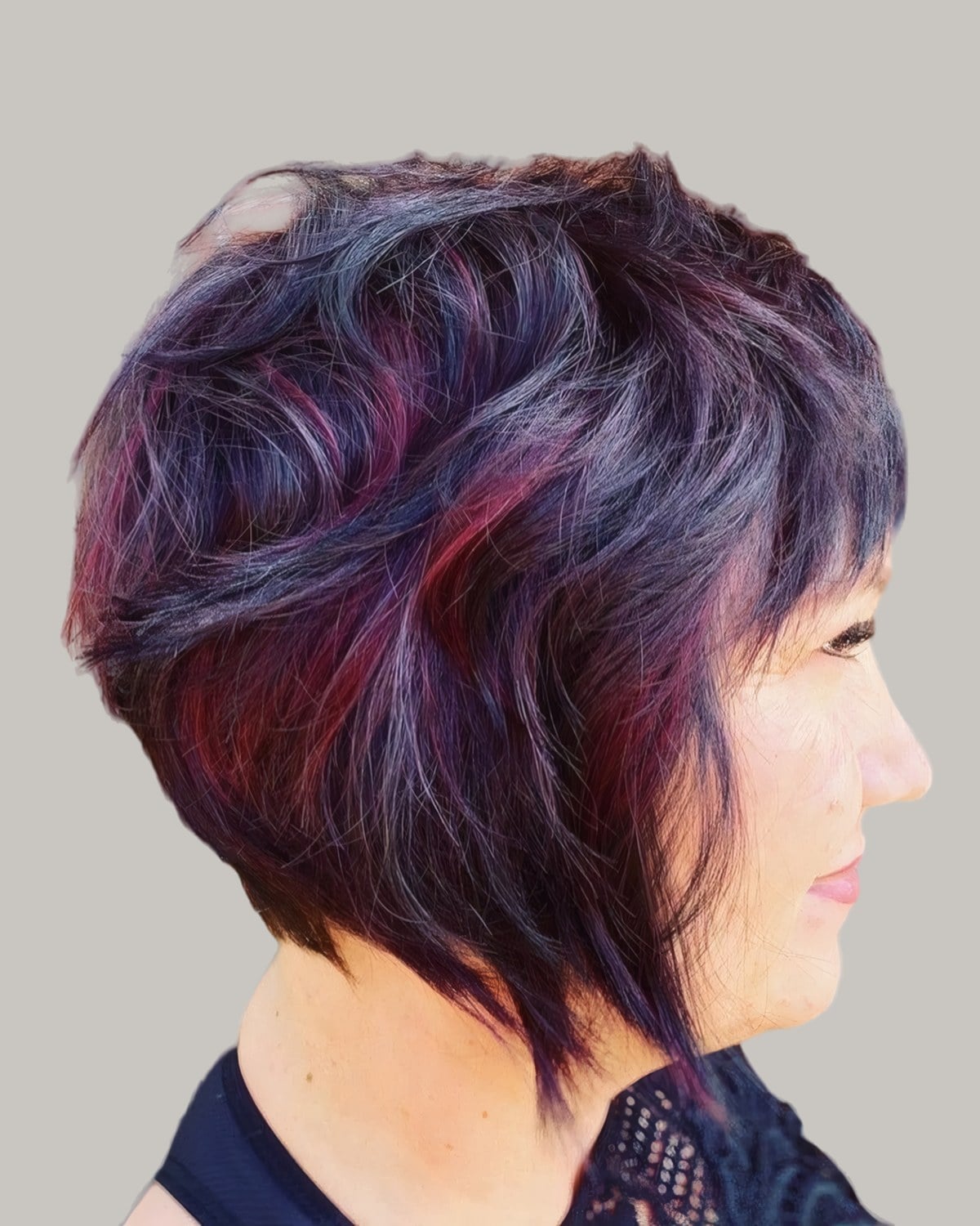 Woman with an angled bob in purple and red tones, in profile