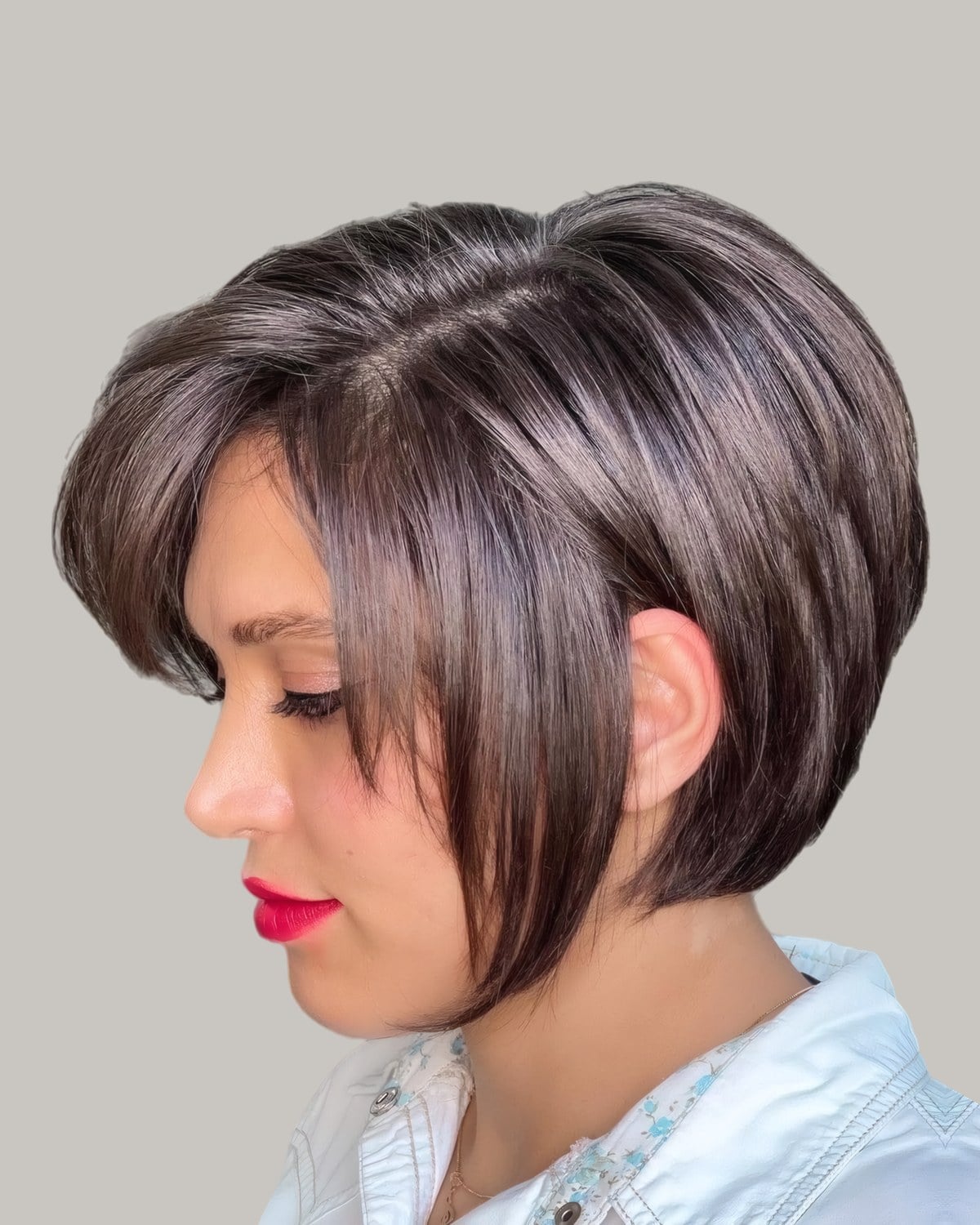 Woman with an ash-brown stacked bob and a long side fringe, looking down