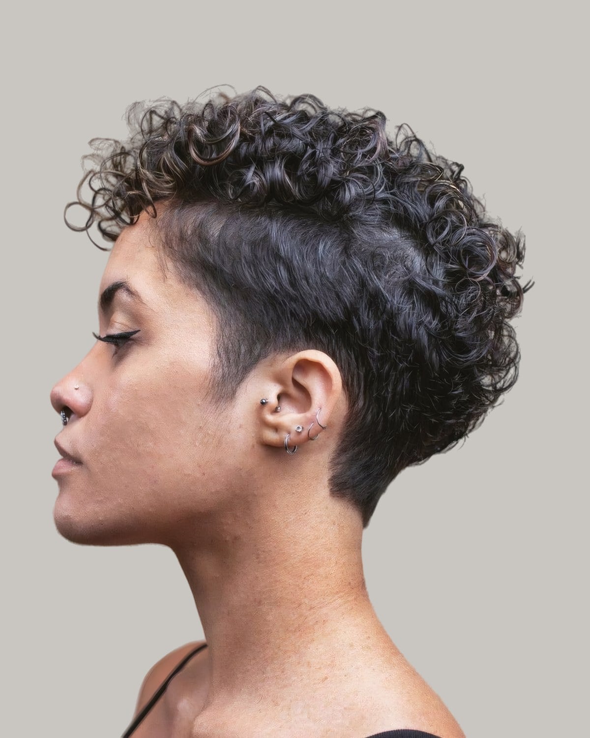 Woman with a curly cut and an undercut at the side, in profile