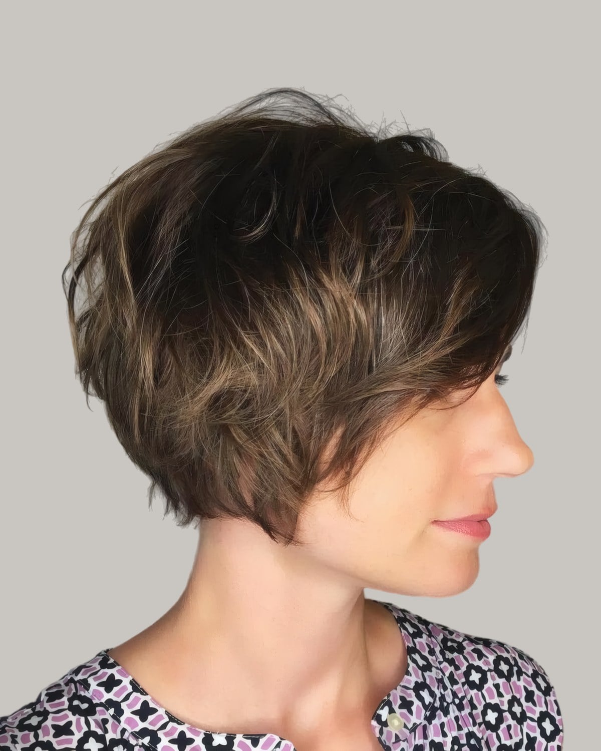 Woman with a layered brown pixie, seen from the side
