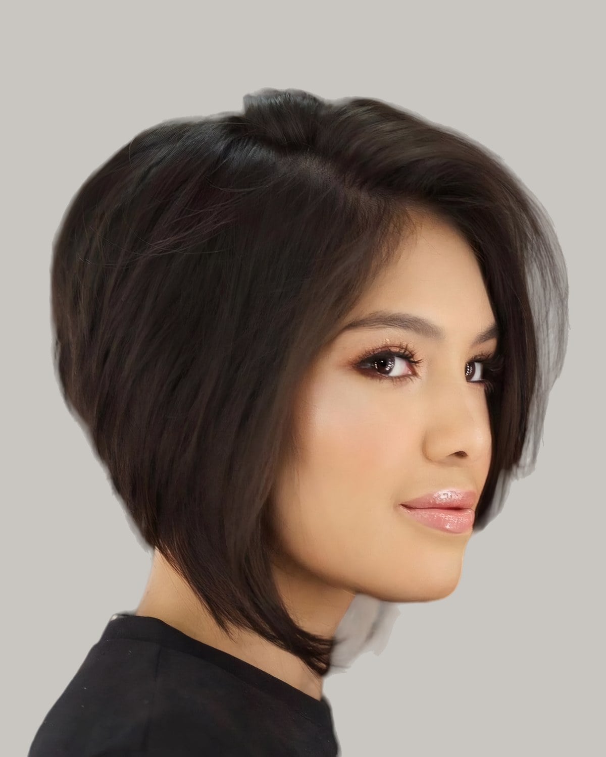 Woman with a dark bob longer in front, looking over her shoulder