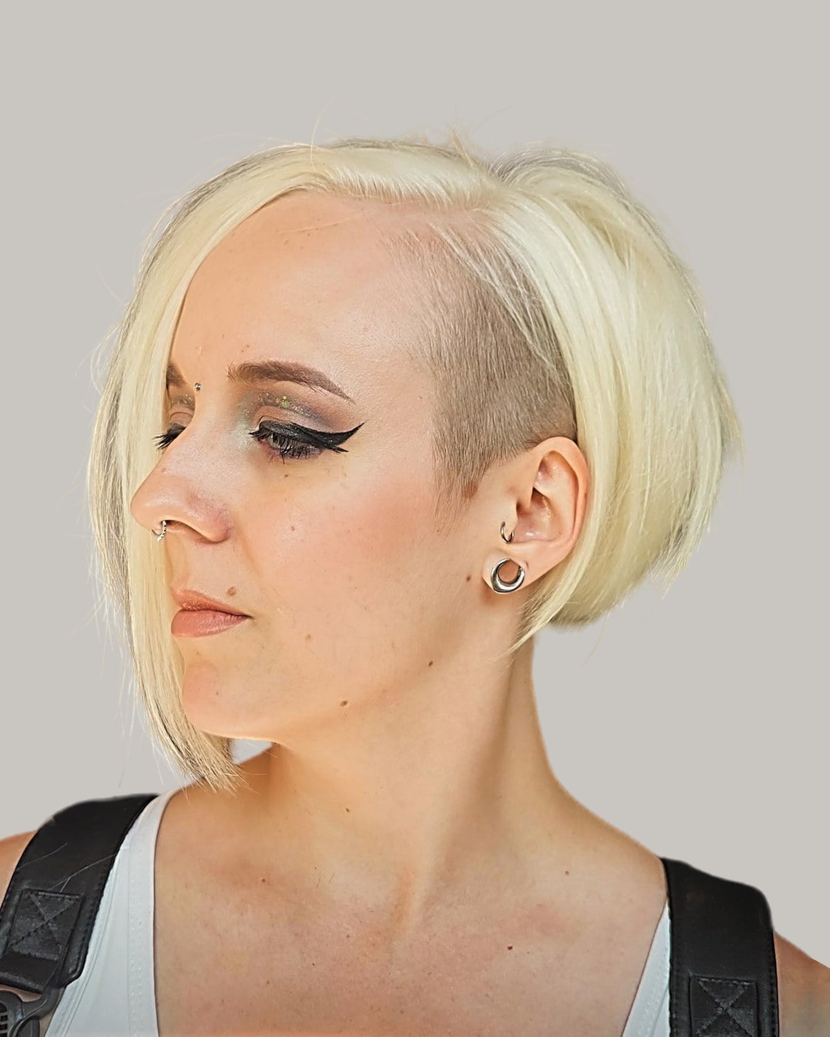 Woman with a platinum bob and a shaved side, in profile