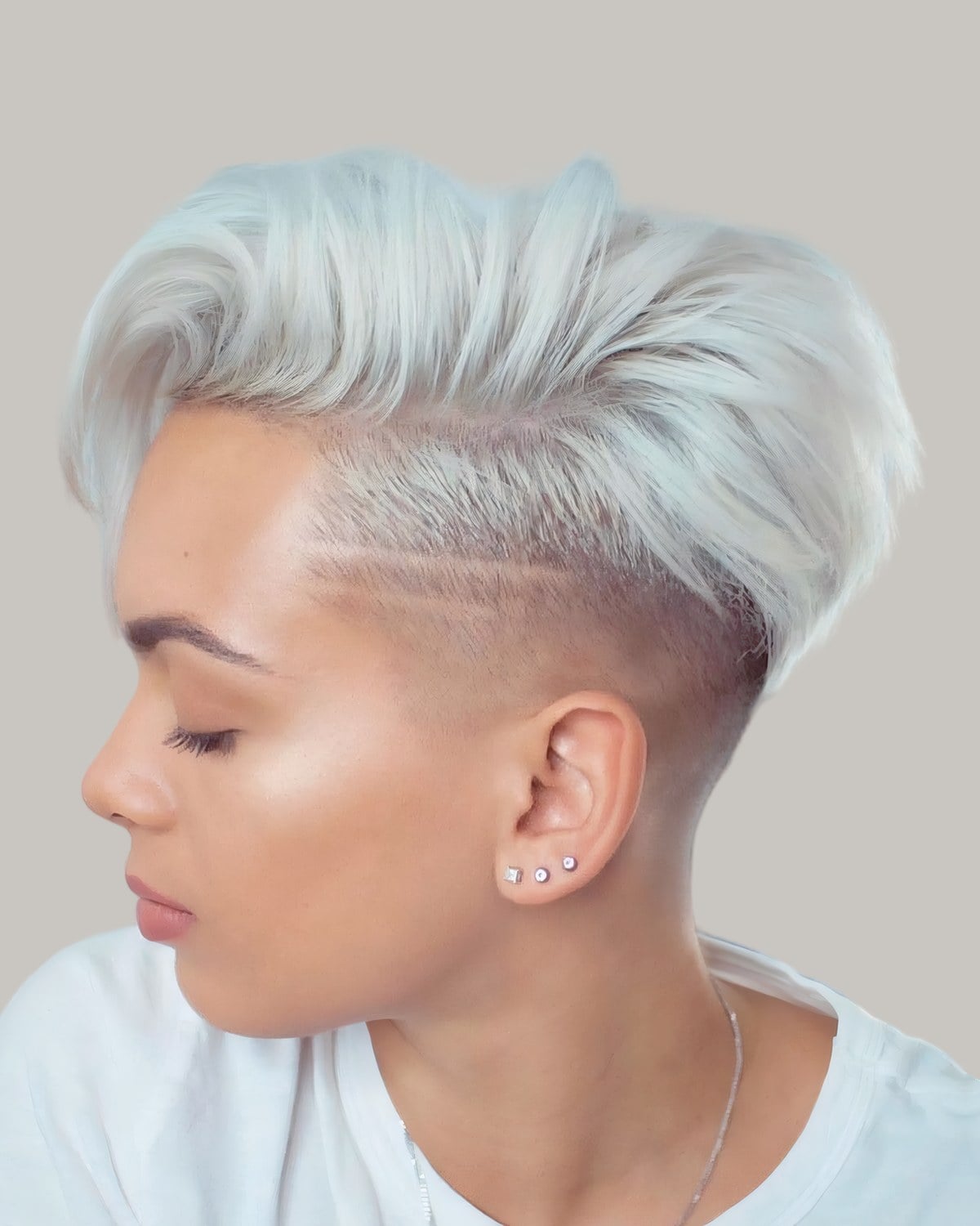 Woman with a white-blonde undercut pixie, eyes lowered