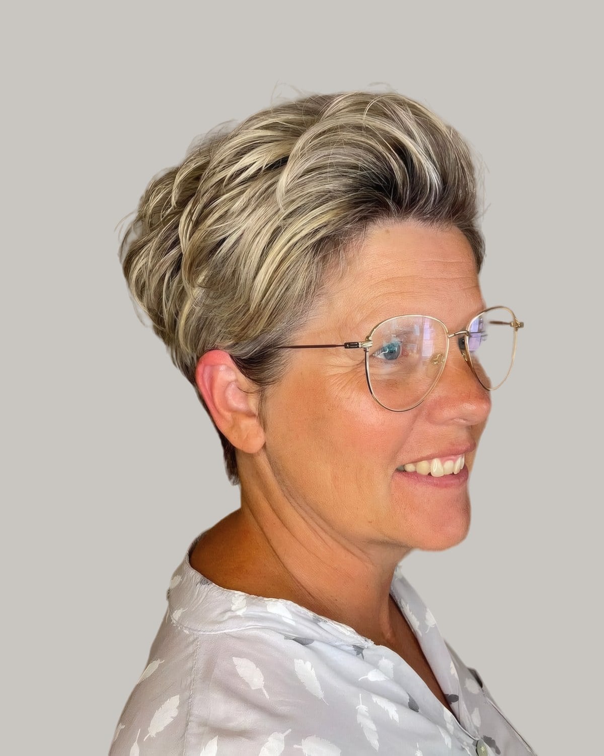 Smiling woman with an ash-blonde pixie swept up at the crown