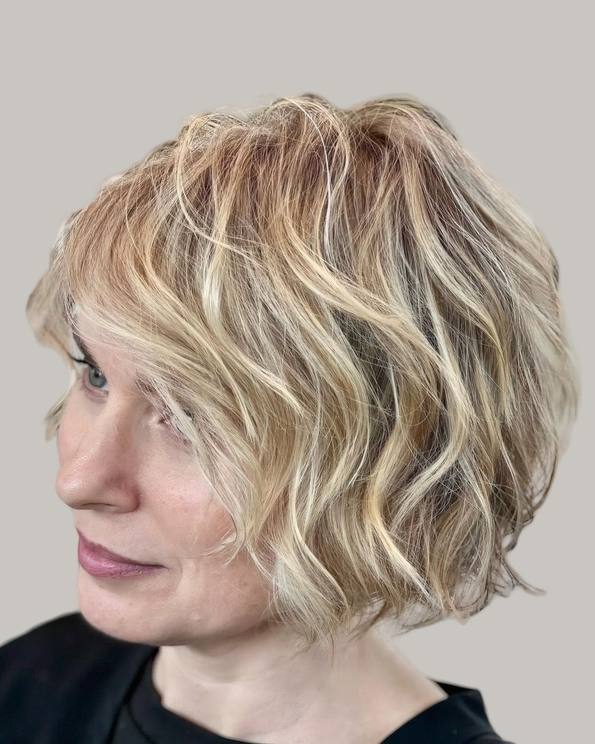 Woman with a wavy blonde short bob, head turned