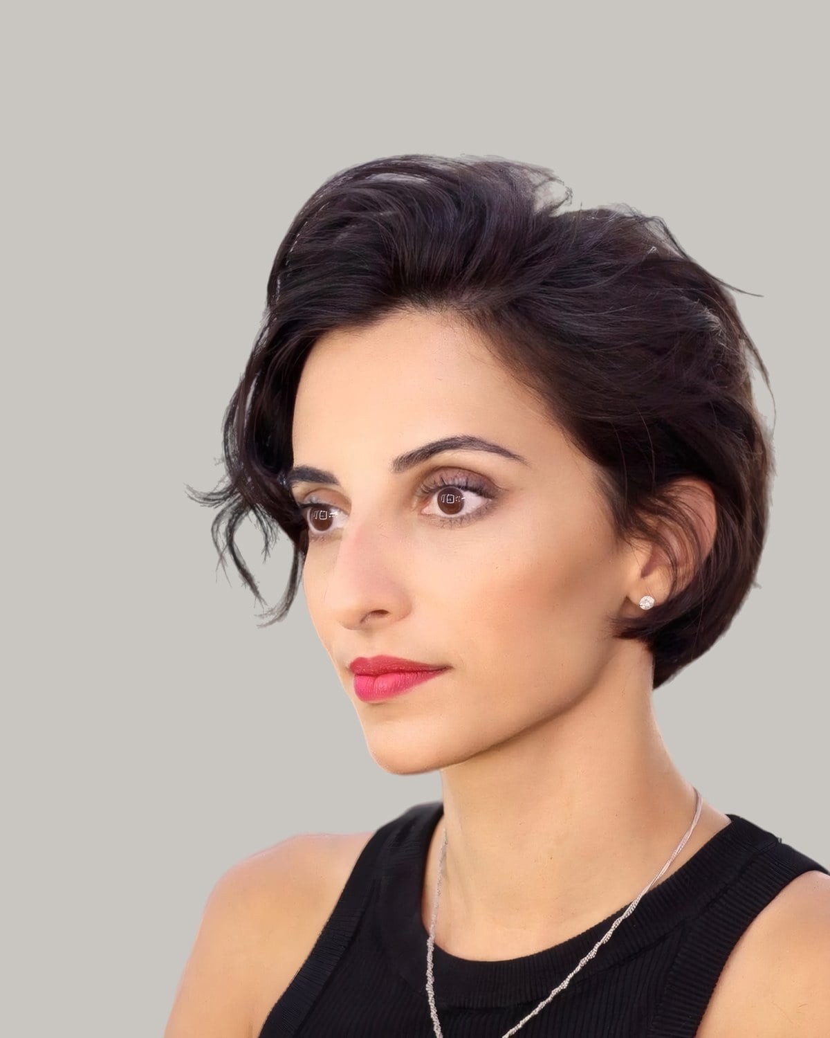 Woman with dark wavy short hair and a side part, looking to the side