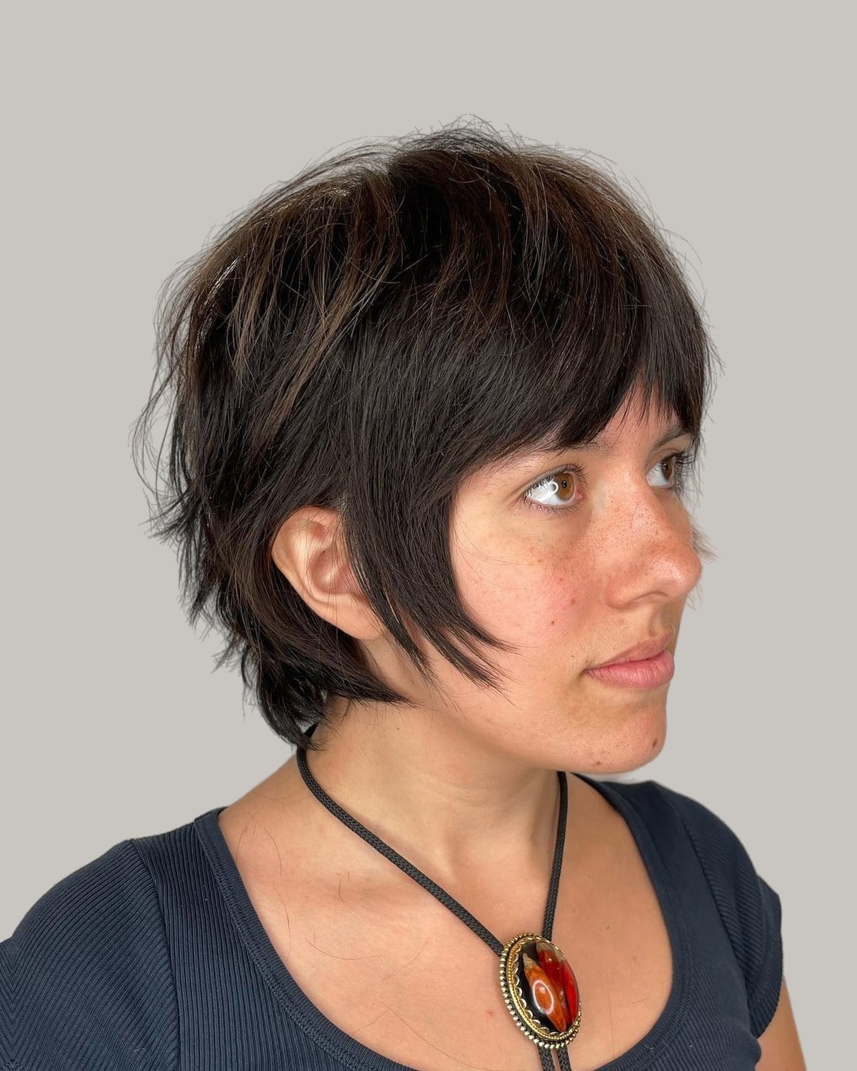 Woman with a dark wolf cut pixie and long side pieces