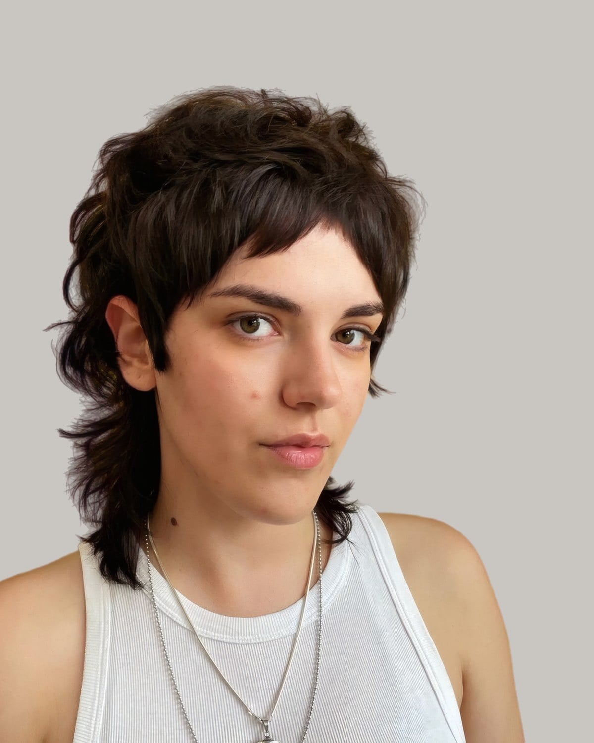 Woman with a dark choppy mullet and short bangs