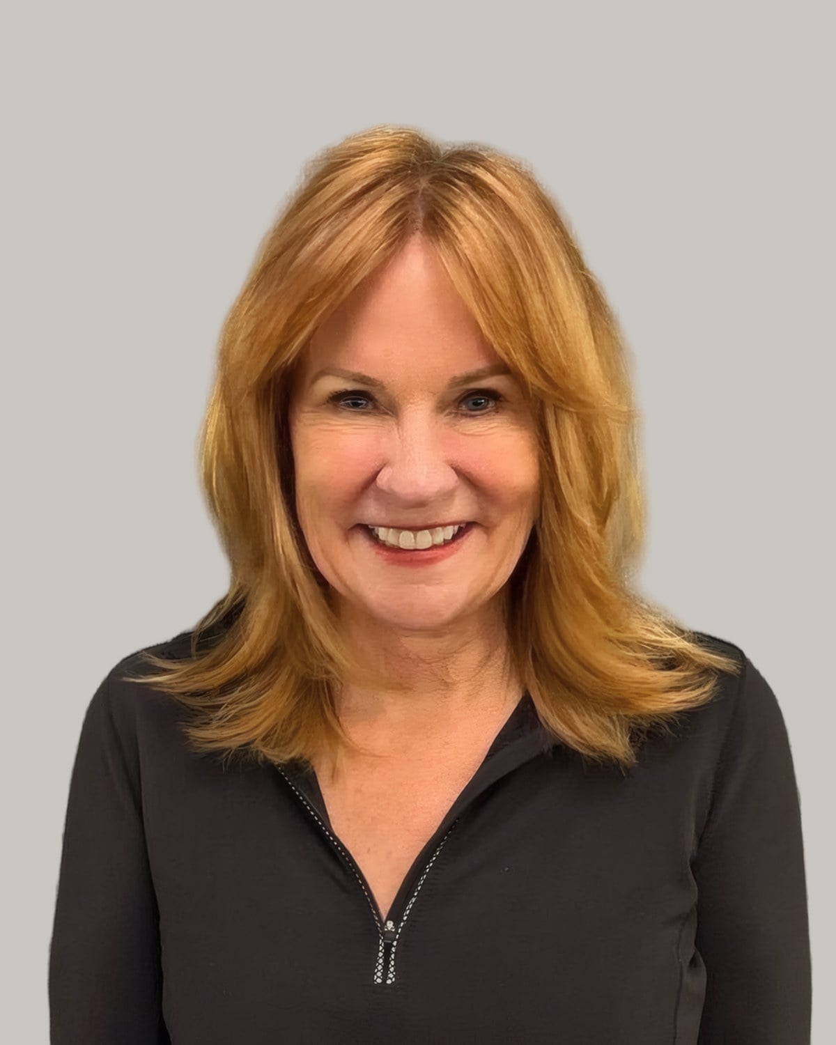 Smiling woman with copper shoulder-length hair and face-framing layers