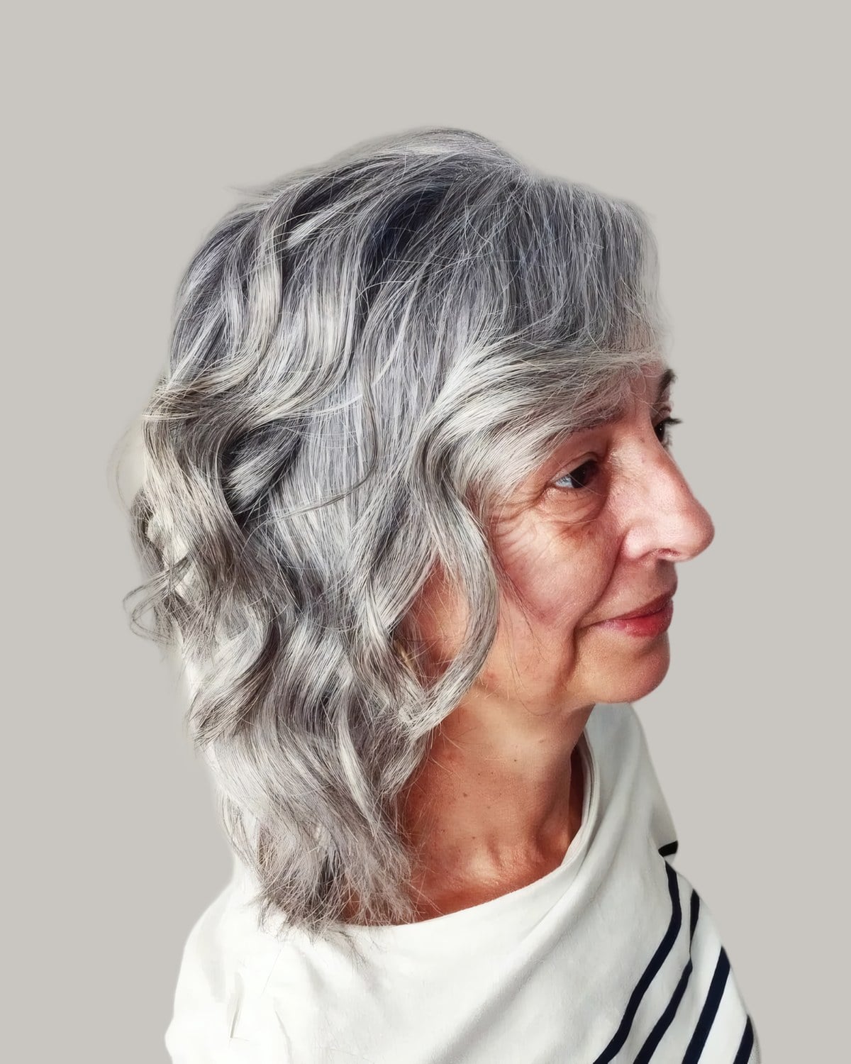 Woman with silver wavy hair to the shoulders, seen in profile