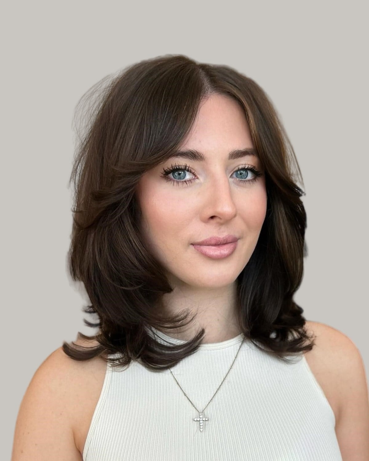 Woman with dark brown hair to the collarbone, curtain bangs and ends flipped out