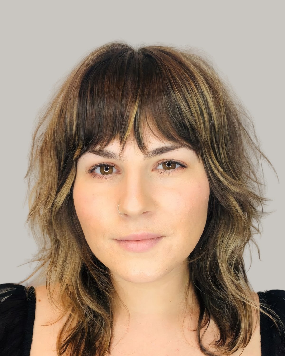 Woman with dark blonde feathered layers, beachy waves and wispy bangs