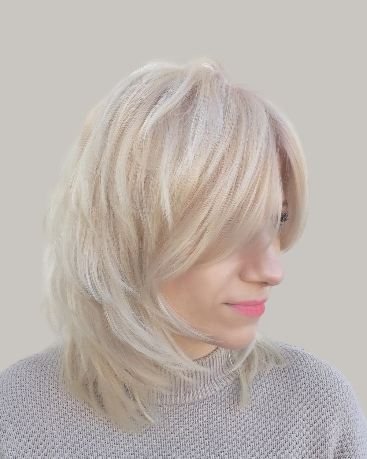 Woman with a platinum shag and a long fringe, seen from the side