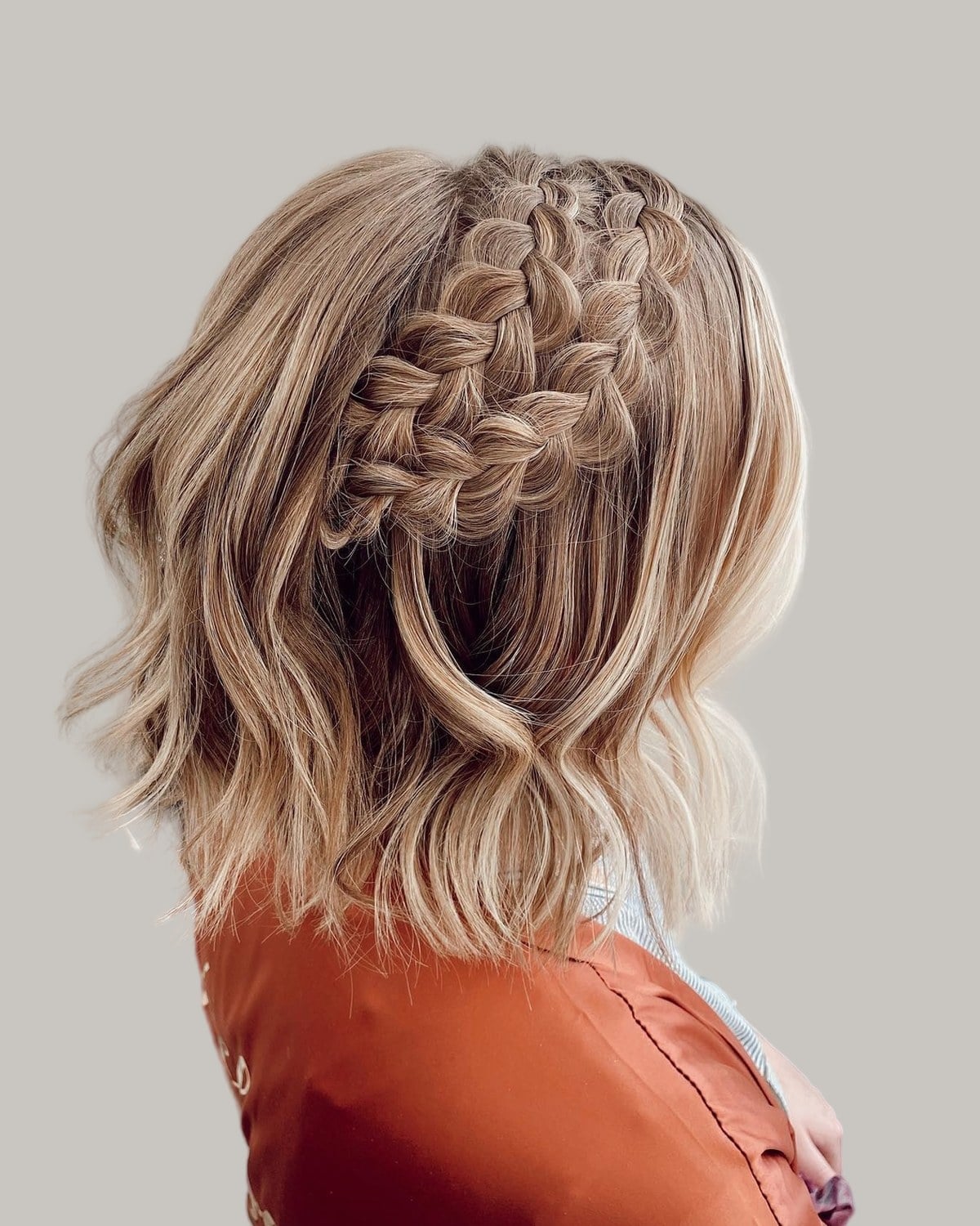 Back view of a wavy blonde bob with Dutch braids across the crown