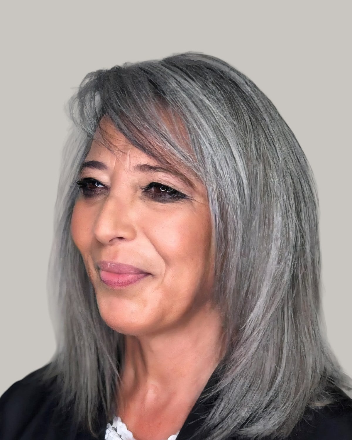 Woman with silver shoulder-length hair, long bangs and straight layers, looking to the side